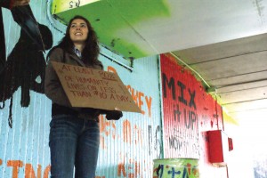 Freshman Tori Bawel stands under the Underpass with a cardboard sign Tuesday morning to promote Homelessness Awareness Week.