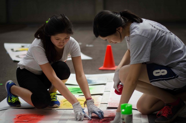 Two freshmen work together to spray-paint hopscotch numbers on the playground at the KIPP Victory Academy Elementary School in St. Louis. Approximately 50 percent of the class of 2018 participated in a variety of community service activites at local schools as part of the Service First program on Saturday, Aug. 30.