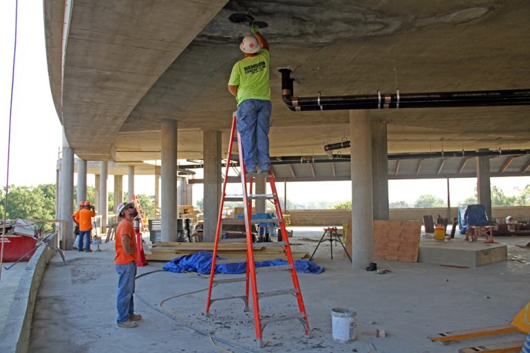 Construction workers apply a layer of concrete to the third-floor ceiling of the new Brown School building. The St. Louis Gateway Arch is clearly visible from the top floor of the building.
