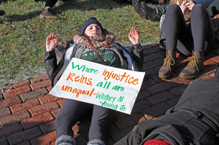 A student lies on the ground in Brookings Quadrangle in the "hands up, don't shoot" pose as she participates in a die-in display.