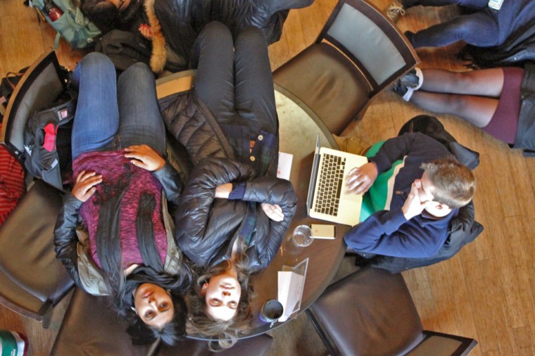 A student continues to work on his laptop, unfazed by the two protesters lying on his table as part of the dead-in.