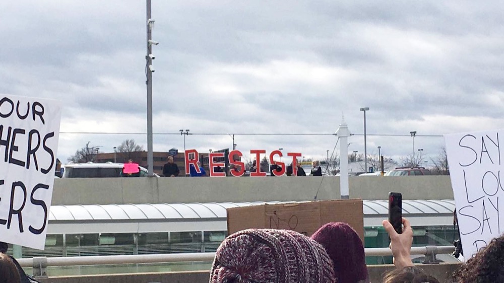 A group of protestors hold up letters spelling out “Resist” during the protest.