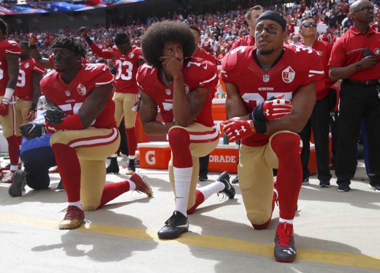 Eli Harold, Colin Kaepernick and Eric Reed kneel during the national anthem before a NFL game. Protests have reached down to the college level as students reconcile with divisive language.  