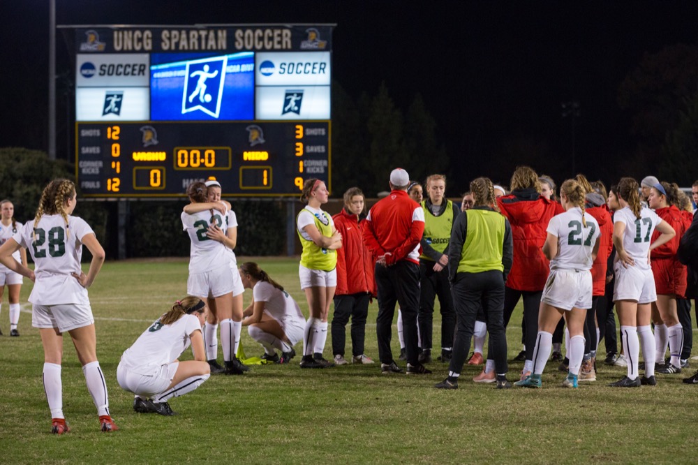 The Washington University women’s soccer team gathers around head coach Jim Conlon at midfield after falling to Middlebury University 1-0 in the semifinals of the NCAA Division III Tournament in Greensboro, N.C. Friday. The Bears’ ended their 2018 season with a nearly perfect 21-1 record.
