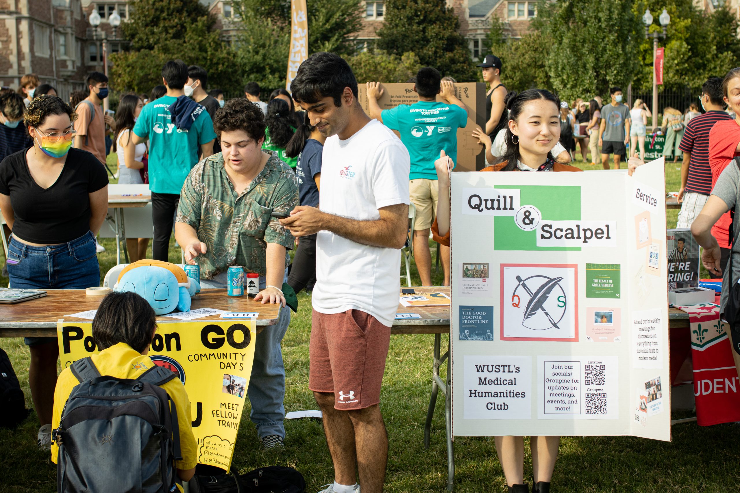 Groups of students stand near posters advertising various clubs.