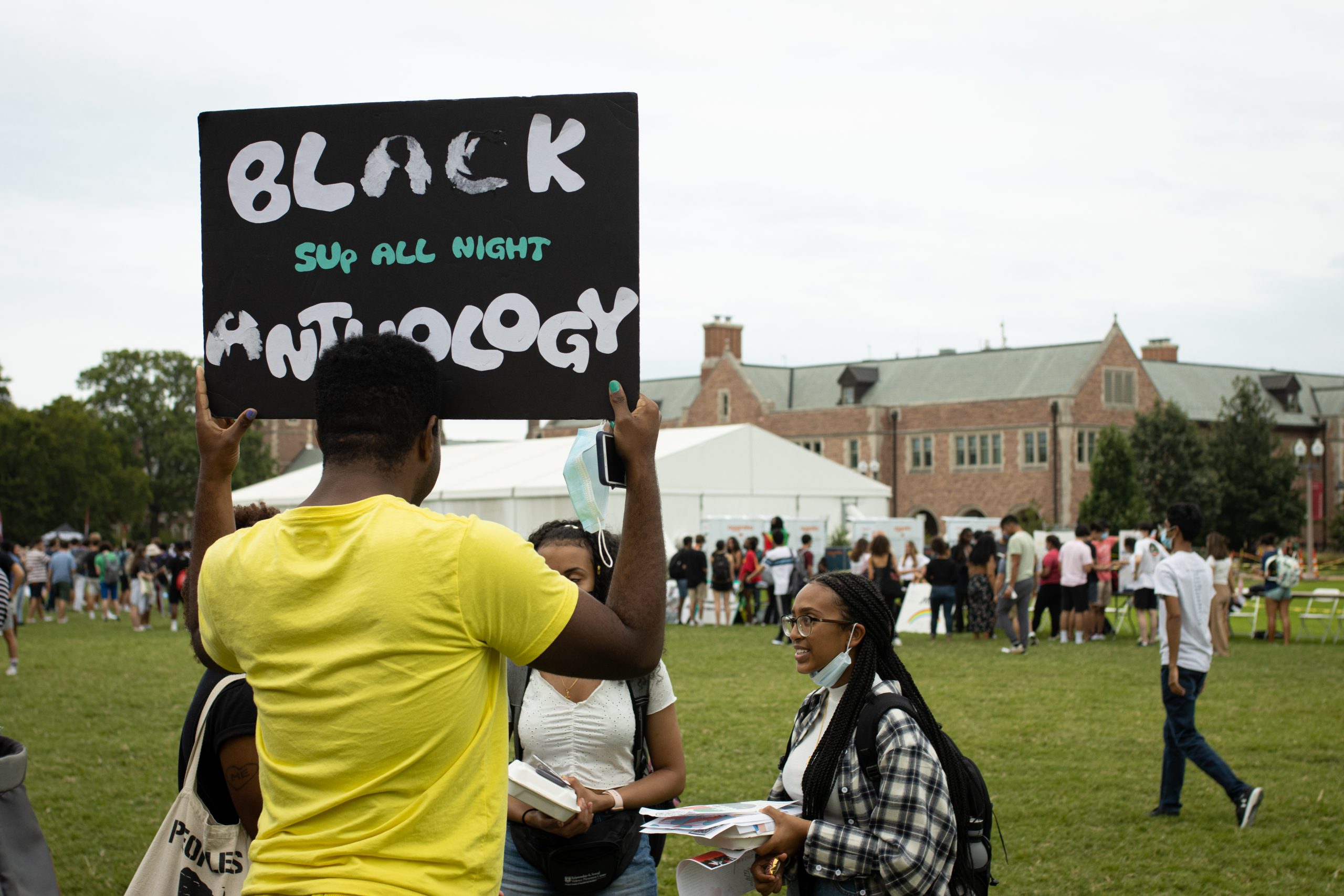 A student holds up a sign reading "Black Anthology."