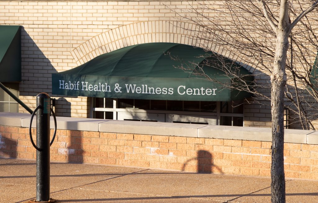 A brick railing sits in front of an awning that reads "Habif Health & Wellness Center"
